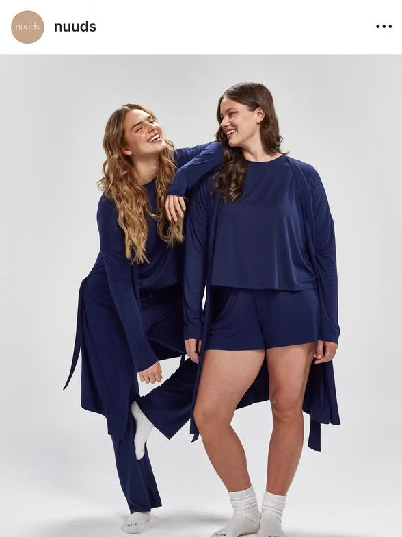Two people in navy pajamas, smiling and posing against a white backdrop.