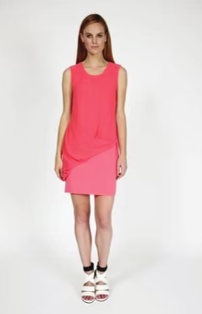 Woman wearing a pink and coral color-block dress and white sandals.