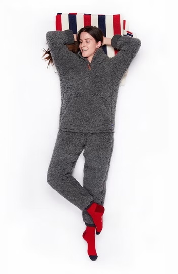 Woman in grey fleece pajamas lying on a pillow, red socks.