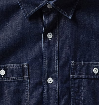 Dark blue denim shirt with white buttons and two chest pockets.
