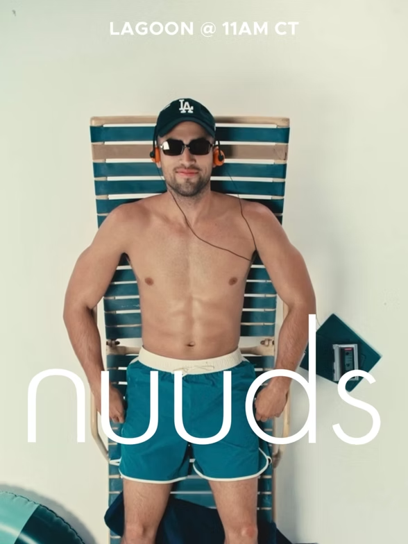 Man in swim trunks, cap, and sunglasses reclines in beach chair; 