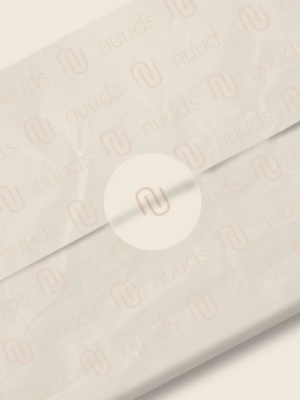 Cream-colored paper package with repeating logo in pale brown; sealed with circular sticker bearing logo.