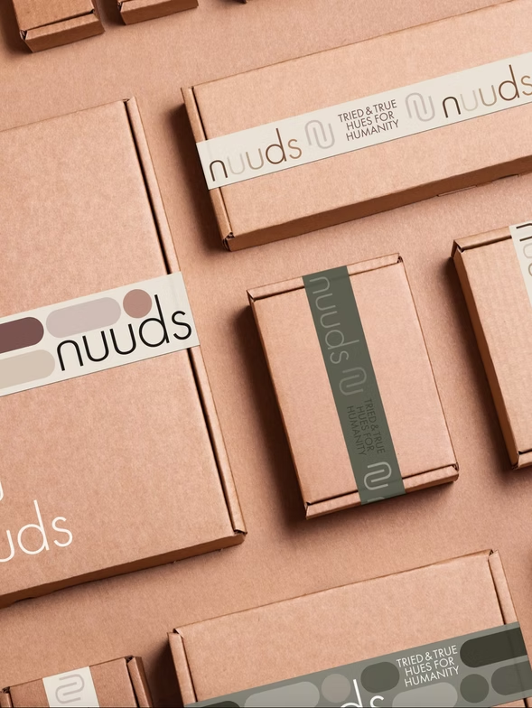 Cardboard boxes with branded labels in shades of brown and green, arranged on a surface.