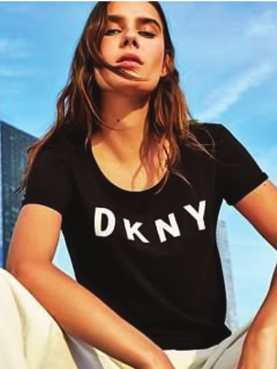 Woman wearing black DKNY t-shirt, sitting outdoors.