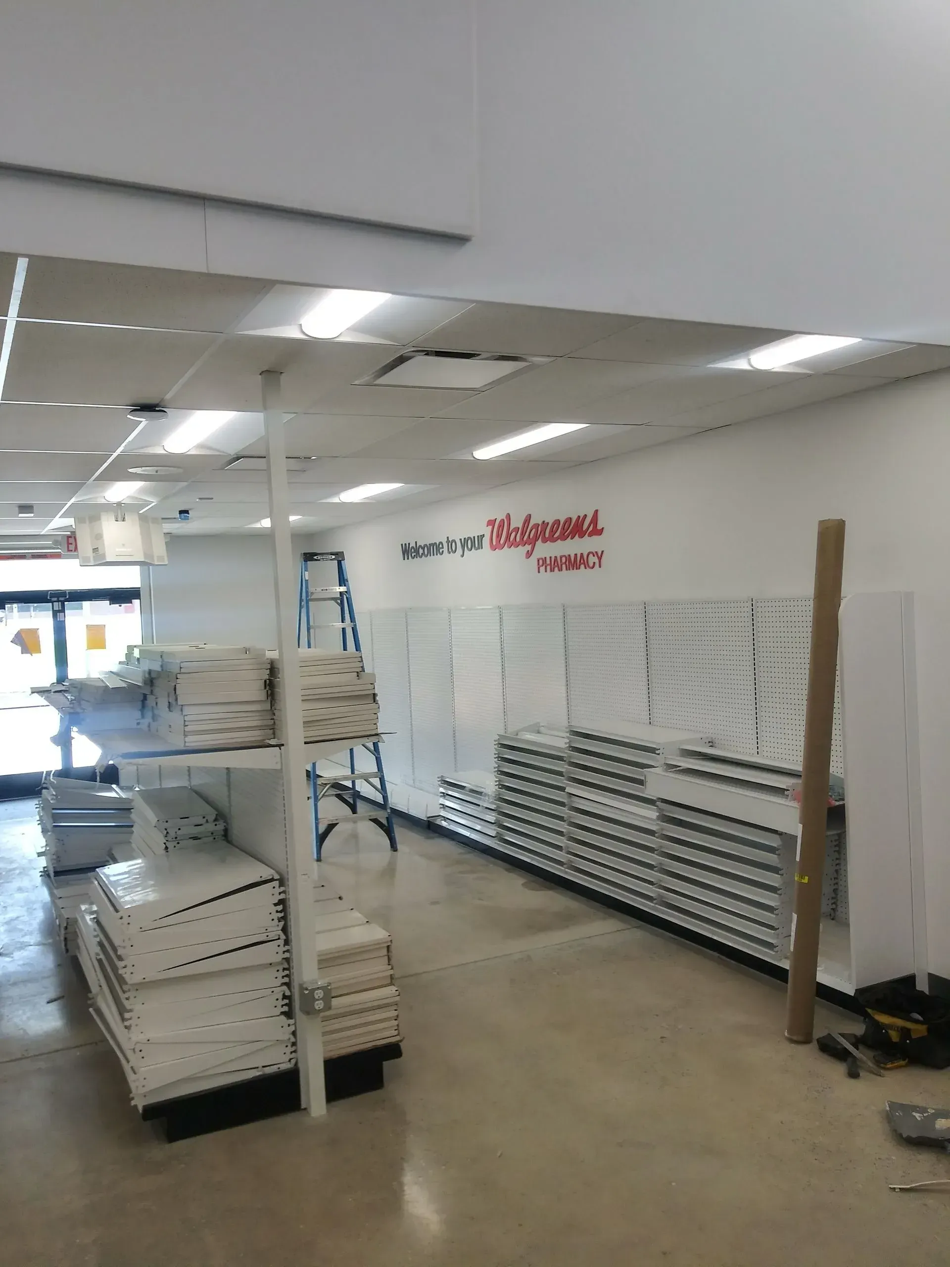 Interior of a Walgreens store under construction, white walls, shelving units, and a ladder.