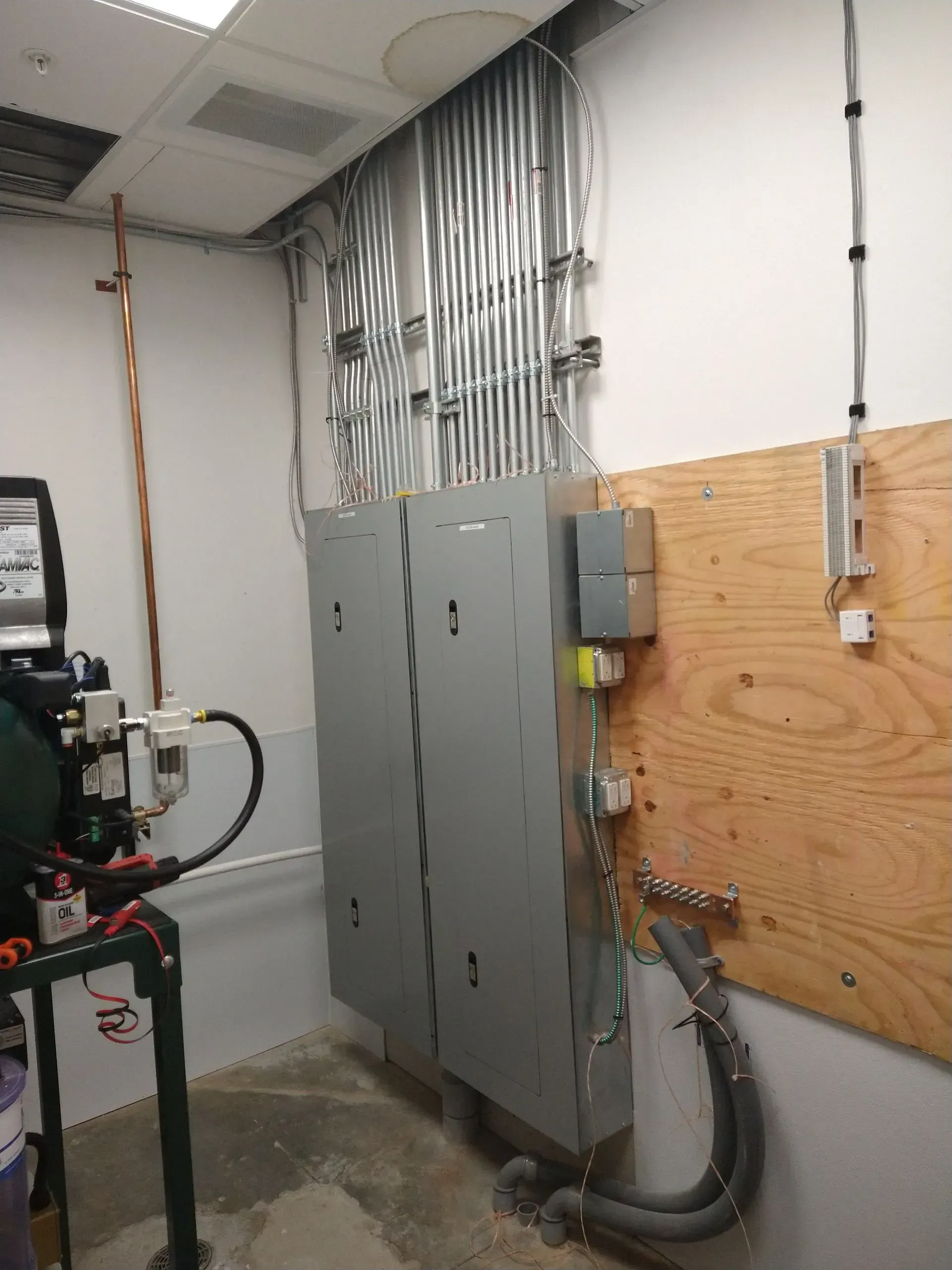 Electrical panel with conduits and wiring on a wall.