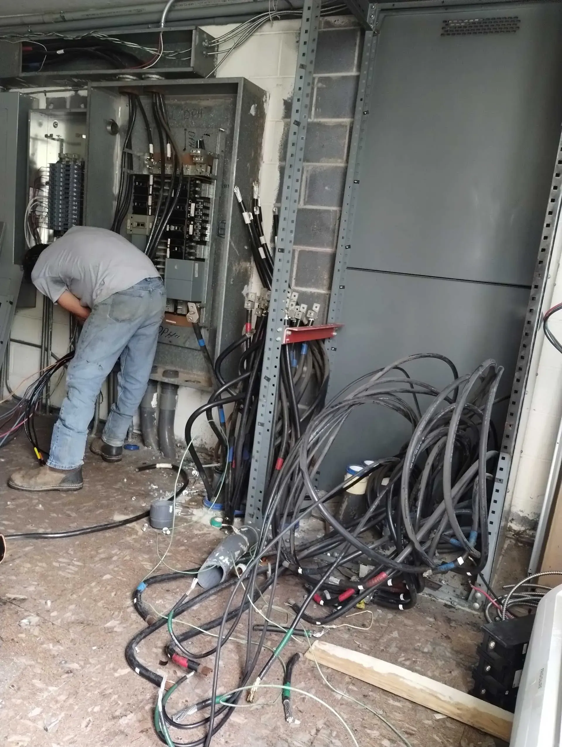 A person working on electrical wiring in an enclosure with cables and components.