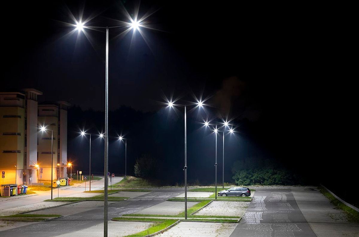 Parking lot at night illuminated by bright street lights.