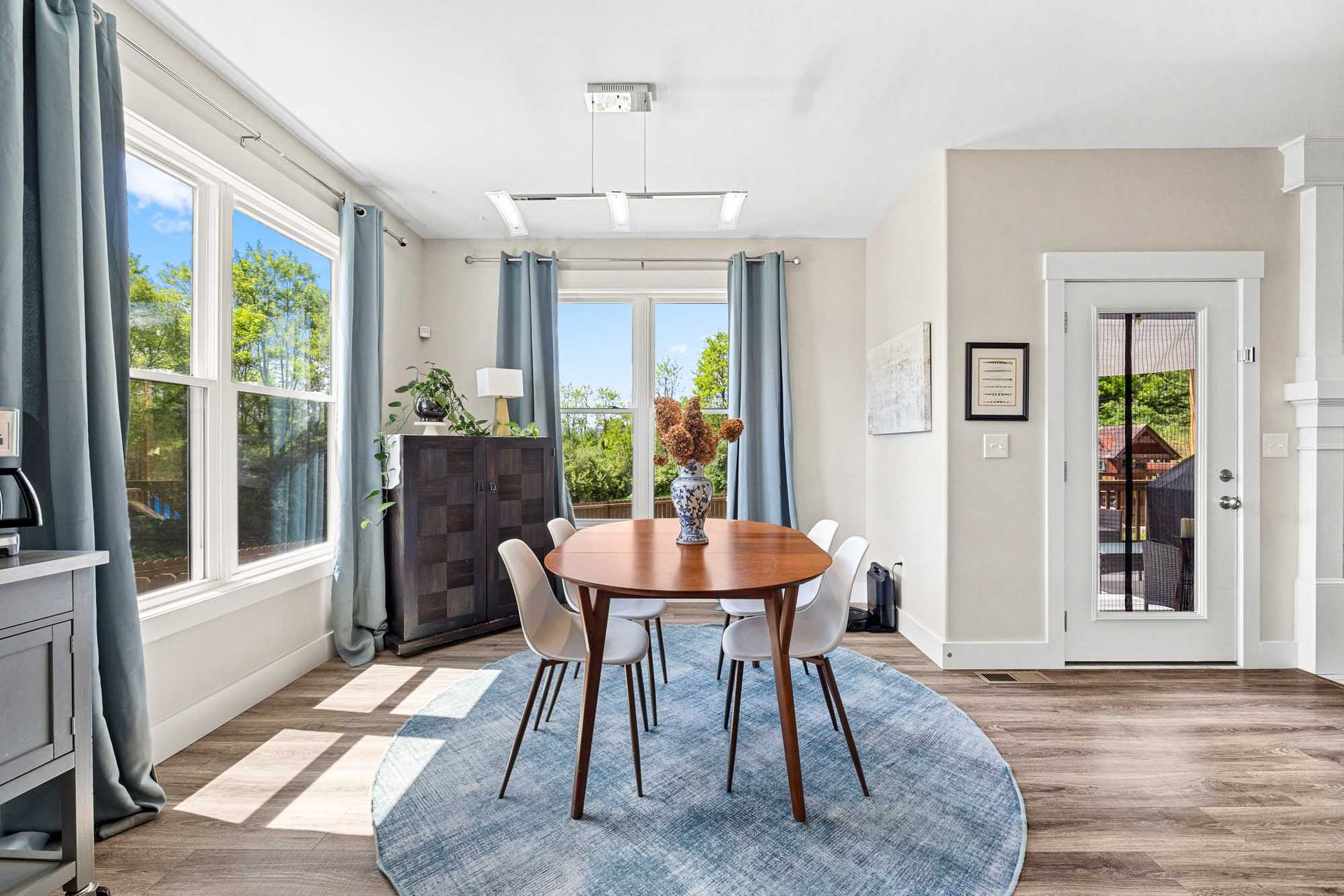 A dining room with a round table and chairs and a blue rug.