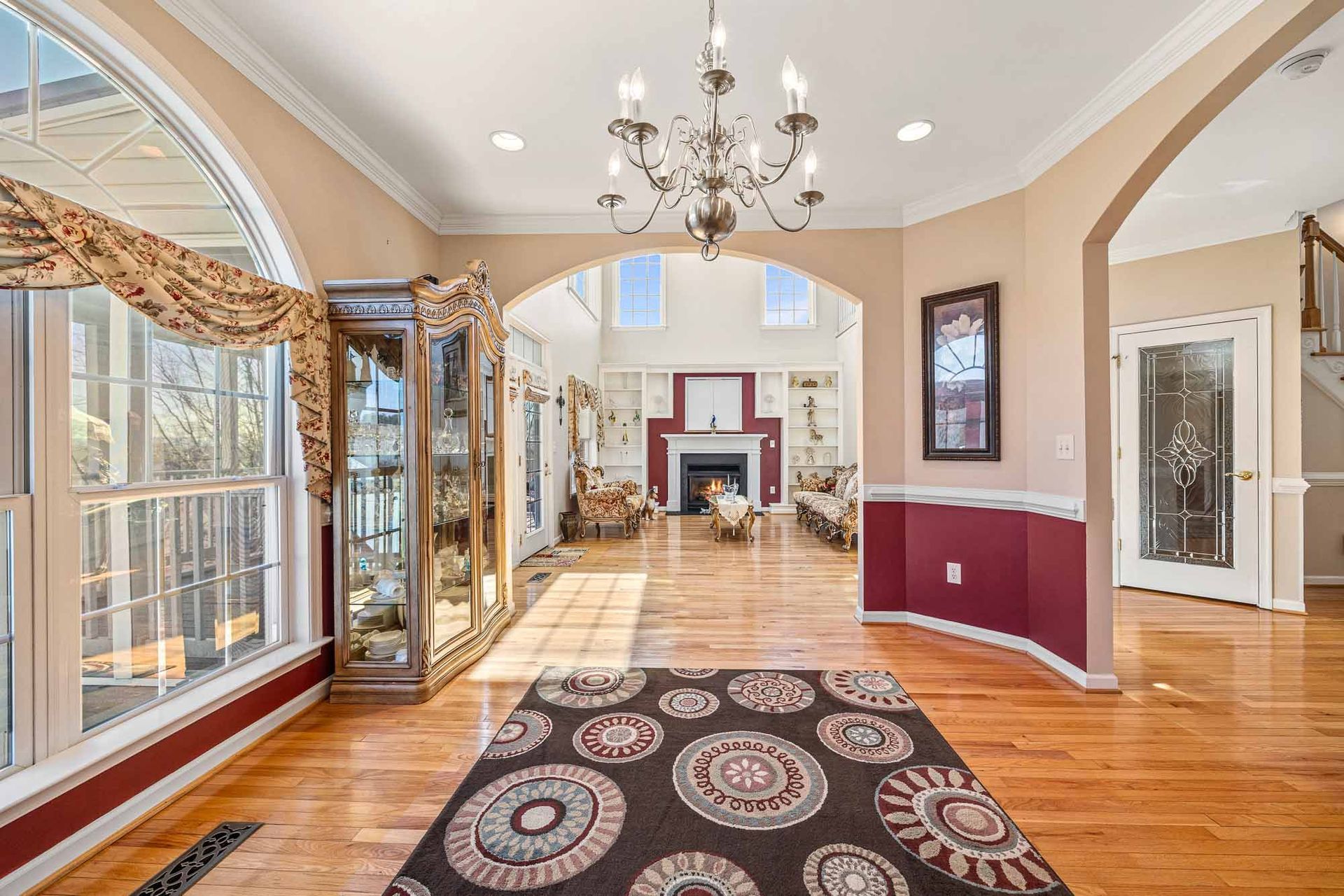A living room with hardwood floors , a chandelier , and a rug.