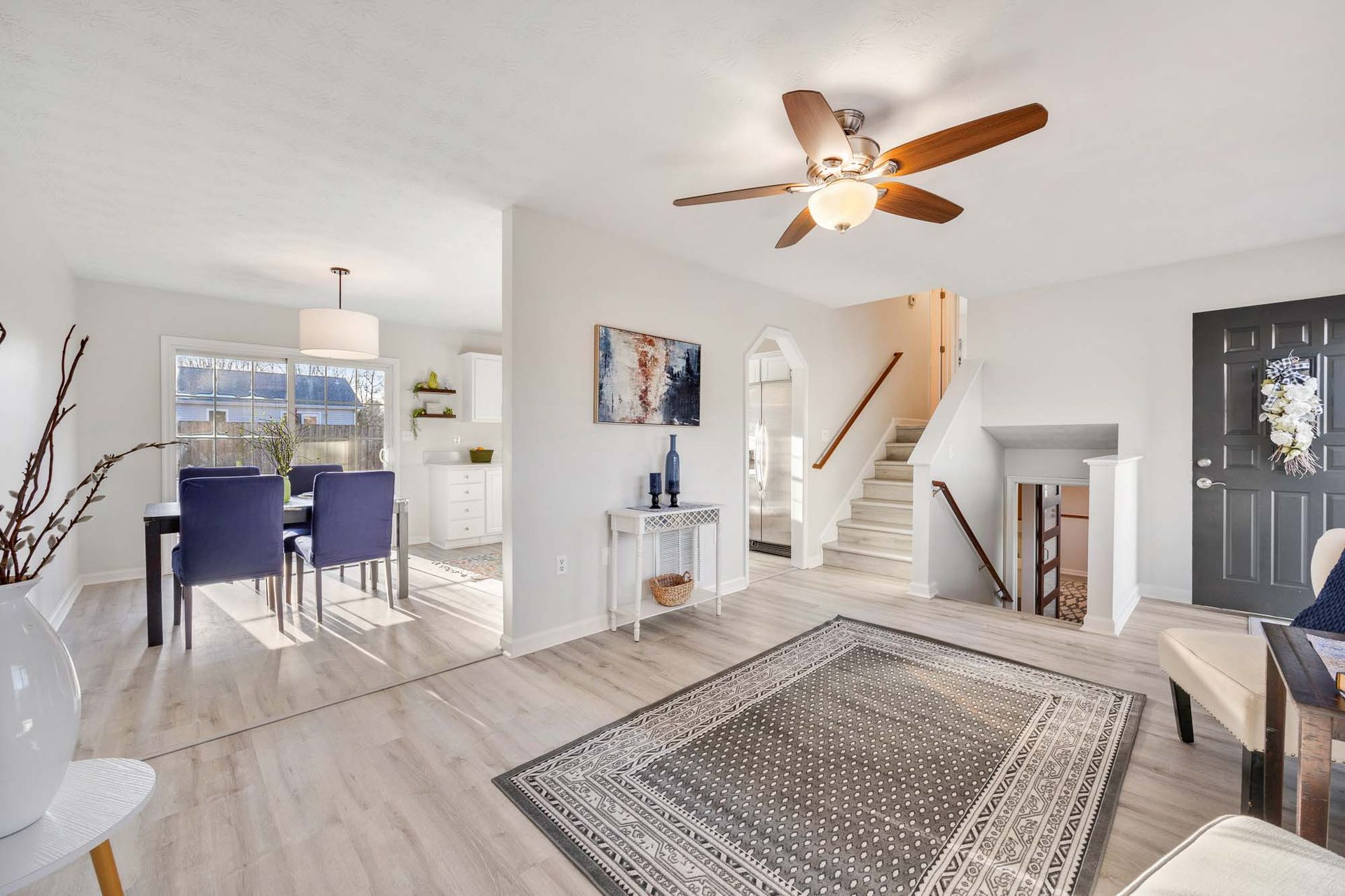 A living room with a rug and a ceiling fan.