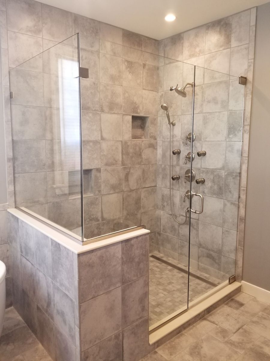 A bathroom with a walk in shower with a glass door.