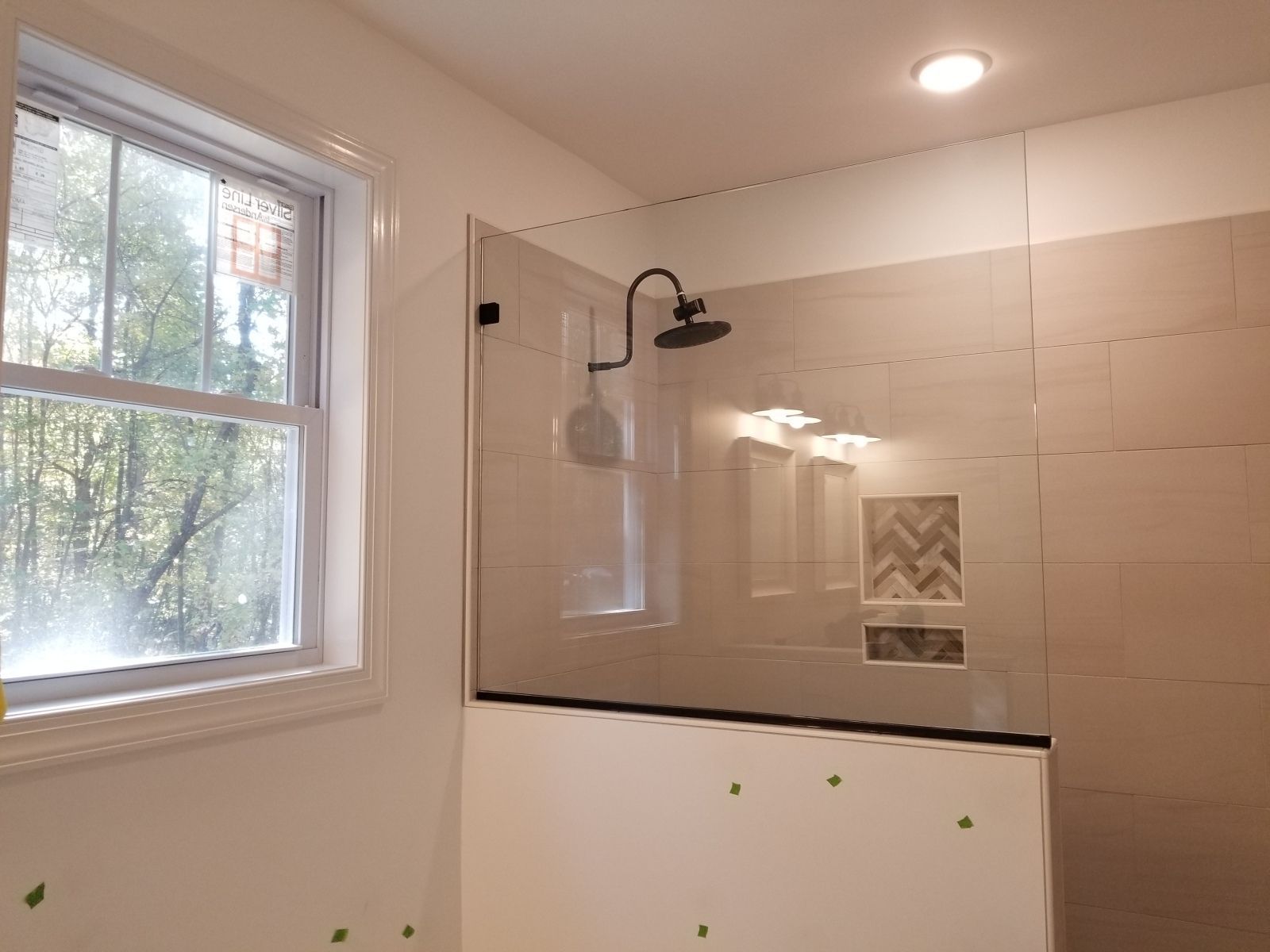 A bathroom with a walk in shower and a window.