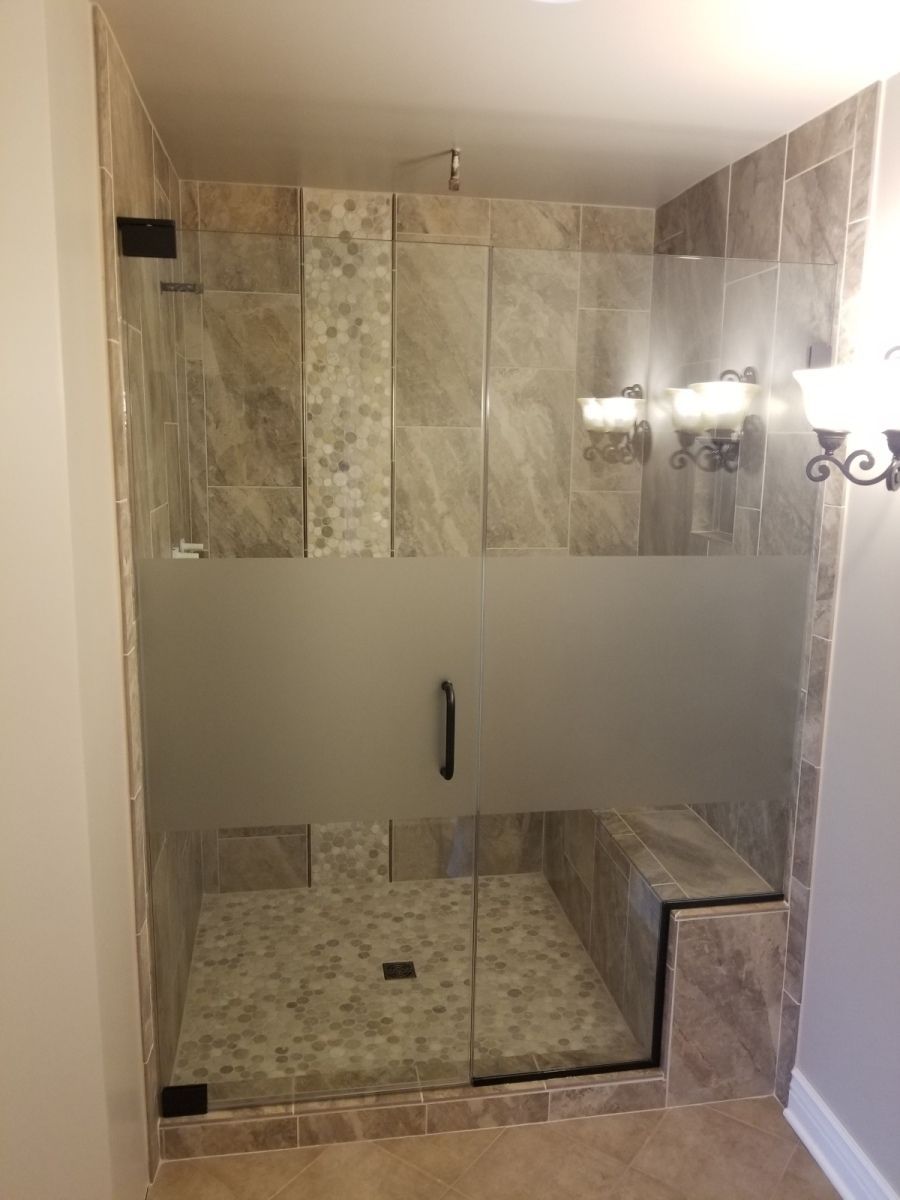 A bathroom with a walk in shower with a frosted glass door.
