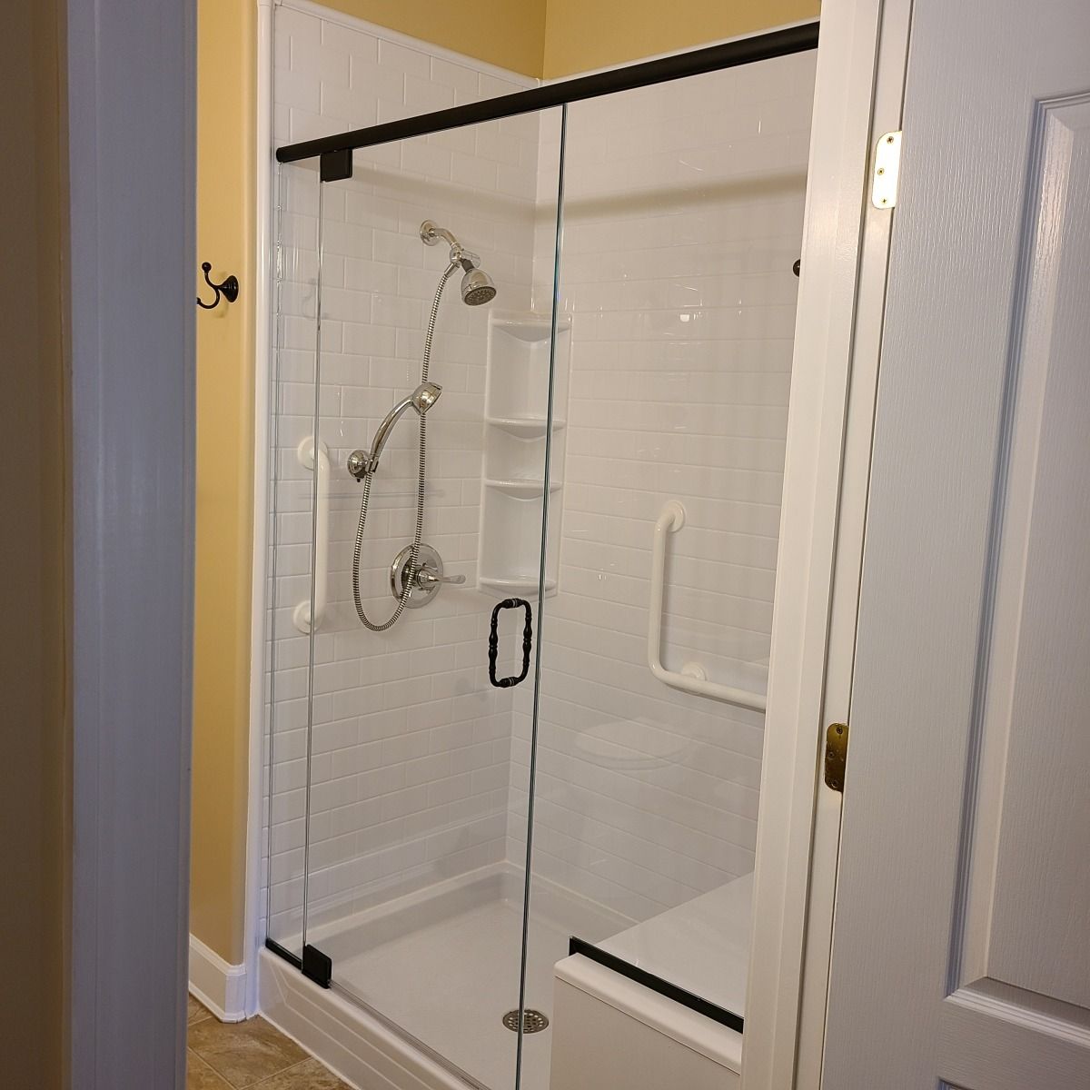 A bathroom with a walk in shower with a glass door