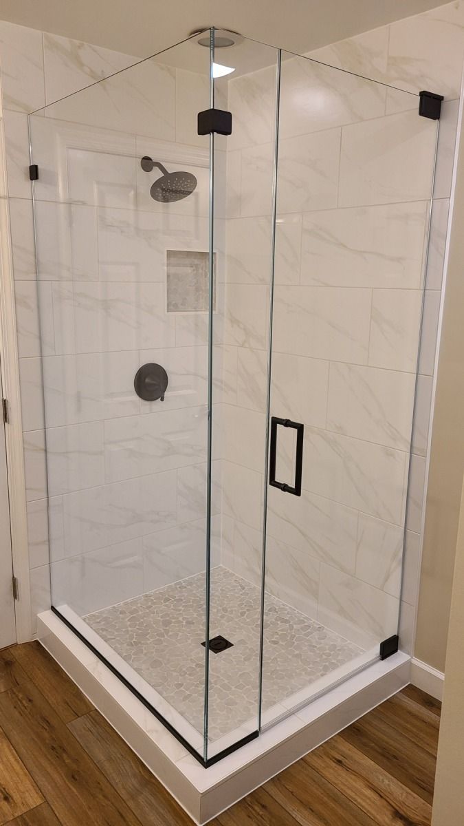 A shower stall with a glass door and a shower head in a bathroom.