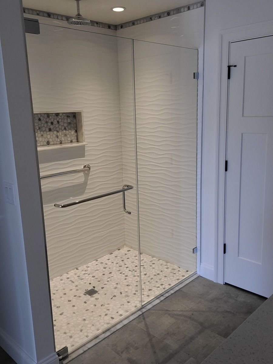 A bathroom with a walk in shower with a glass door
