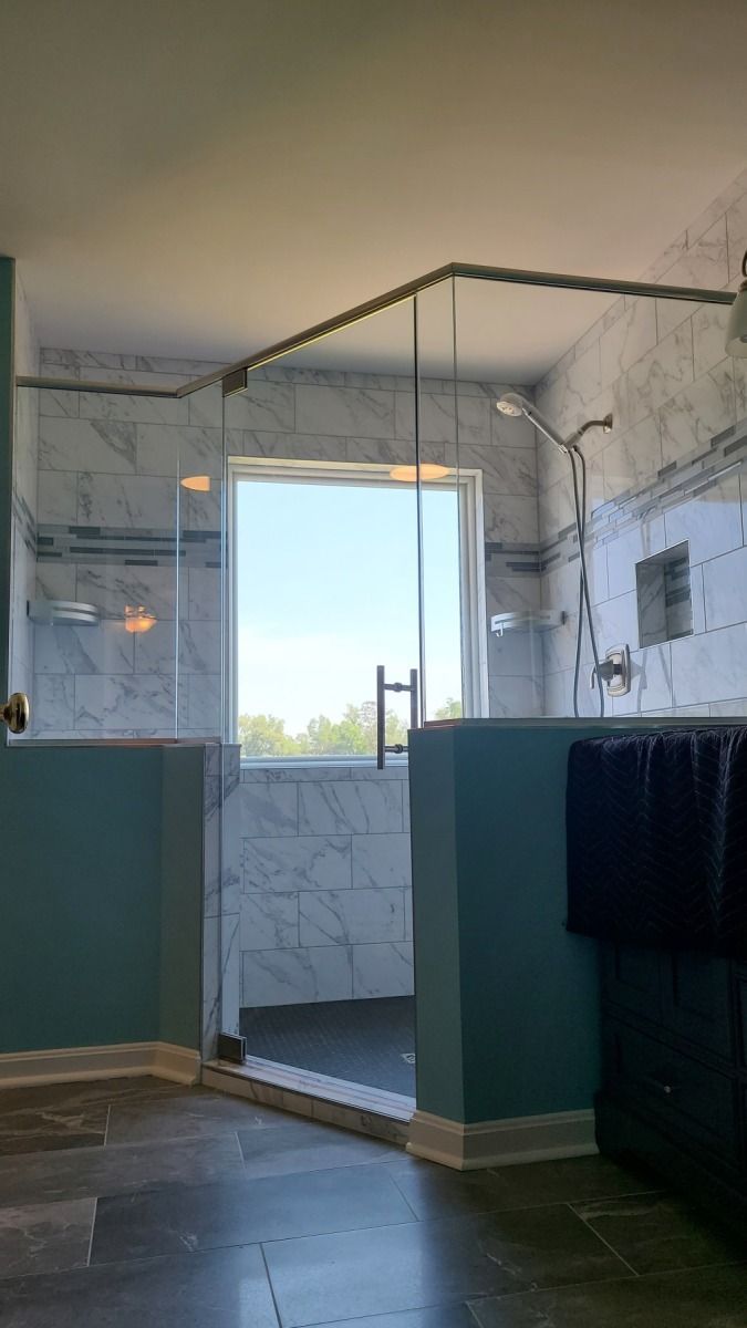 A bathroom with a walk in shower and a window.