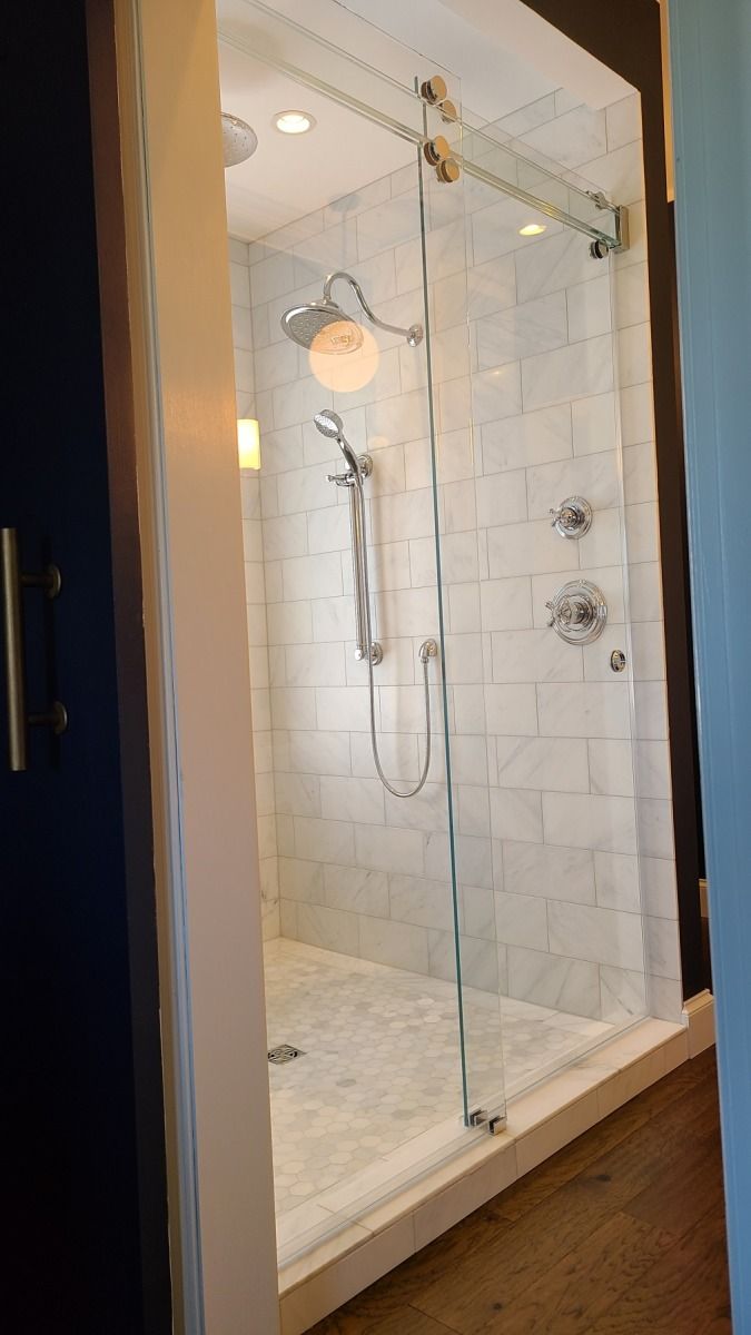 A shower with a sliding glass door and a shower head.
