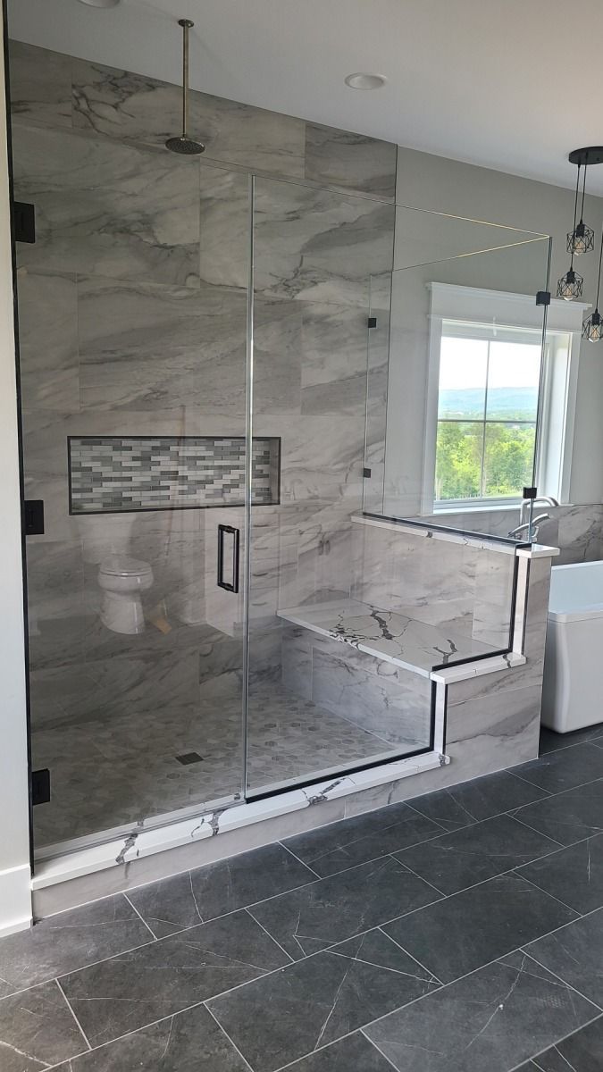 A bathroom with a walk in shower and a window.