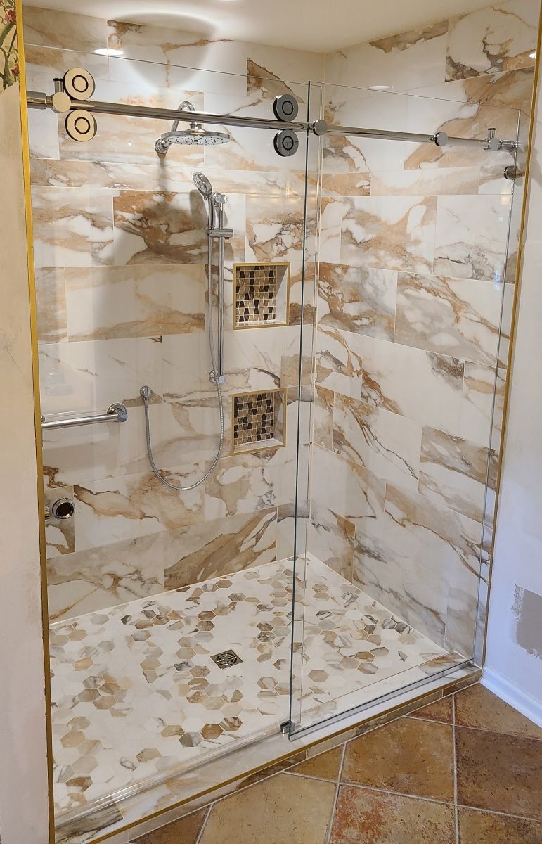 A bathroom with a walk in shower with a glass door.