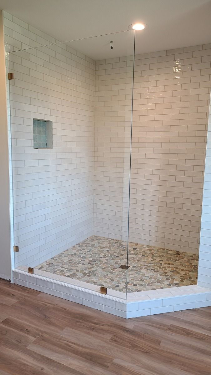 A bathroom with a walk in shower with a glass door.