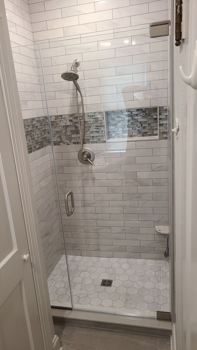 A bathroom with a walk in shower with a glass door.