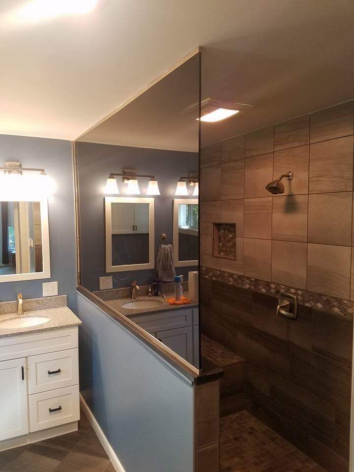 A bathroom with a walk in shower , sink and mirror.
