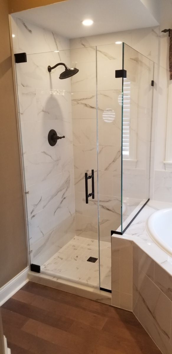 A bathroom with a walk in shower and a tub.