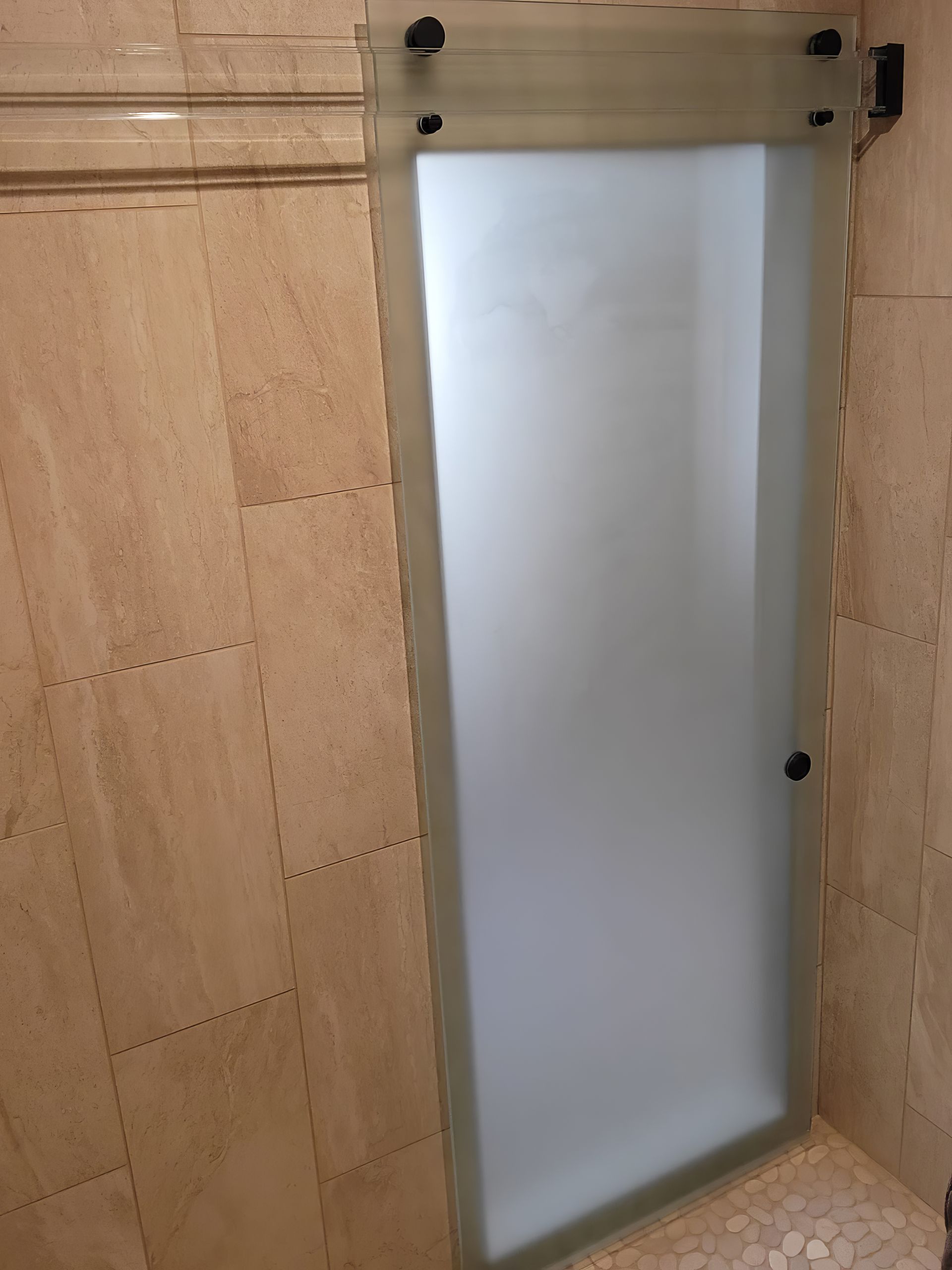 A glass shower door in a bathroom with a marble wall.