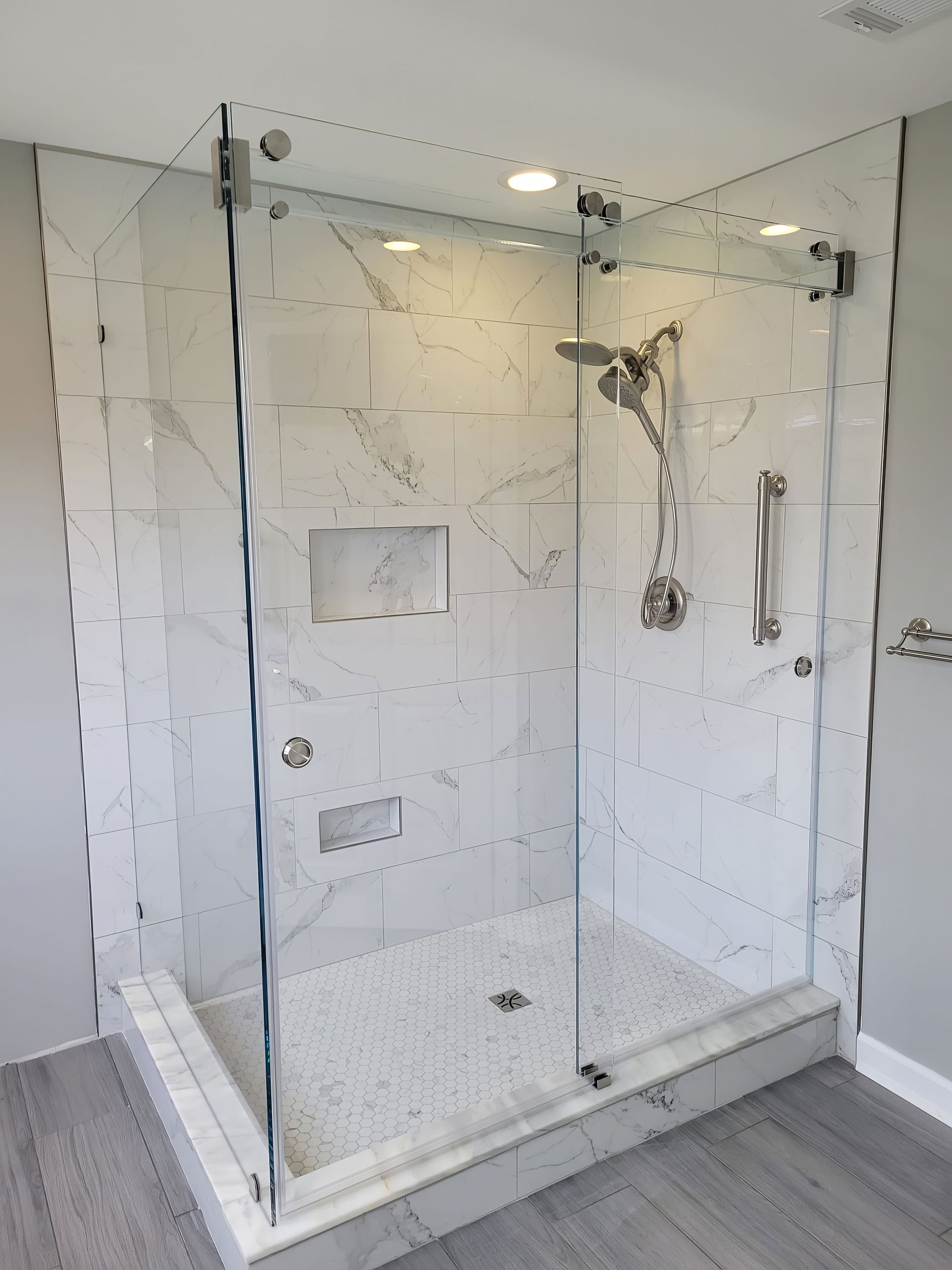 A bathroom with a walk in shower with a glass door.