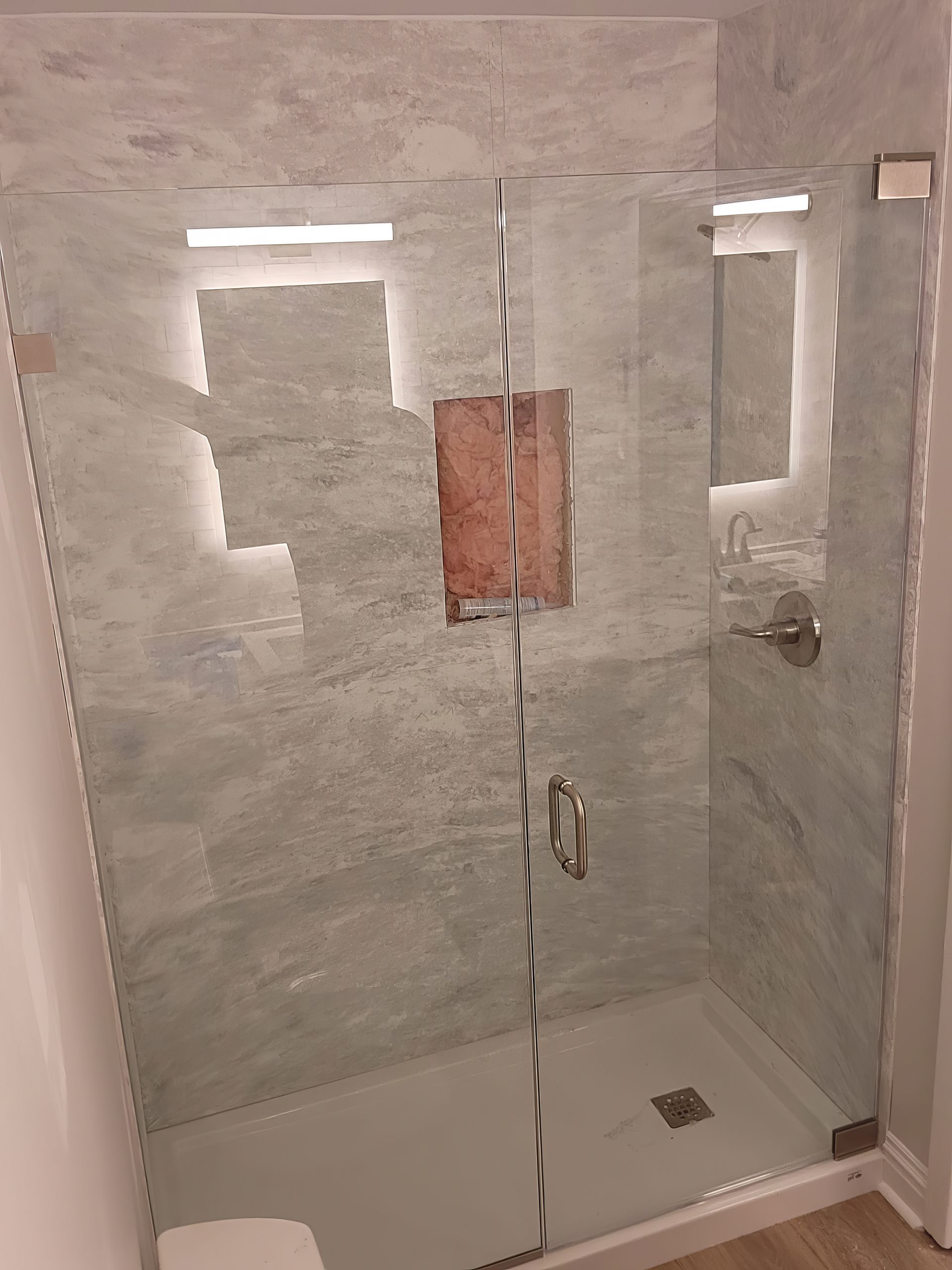 A bathroom with a glass shower door and a toilet.