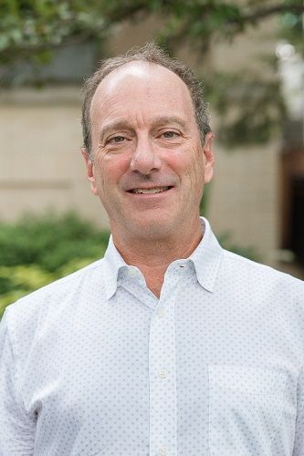 A man and a woman are sitting on a dock overlooking a lake.