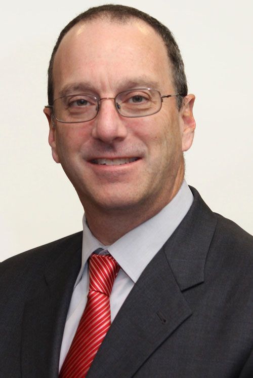 A man in a suit and tie is smiling for the camera