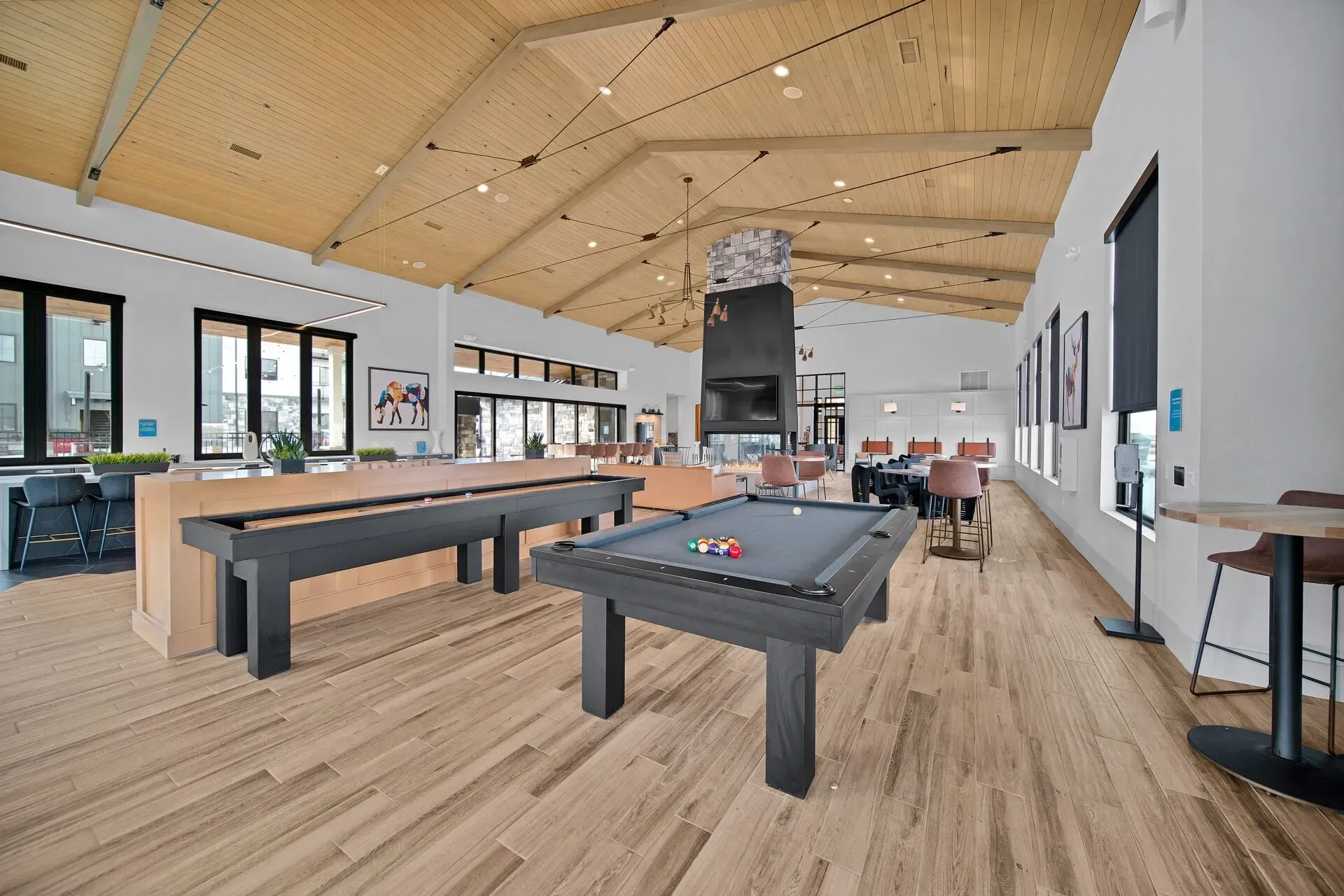 Clubhouse lounge with pool table and shuffleboard, fireplace and seating areas.