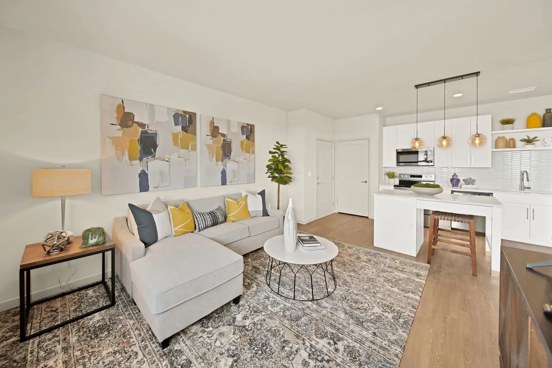 Living room with sectional sofa, coffee table, and open-concept kitchen.