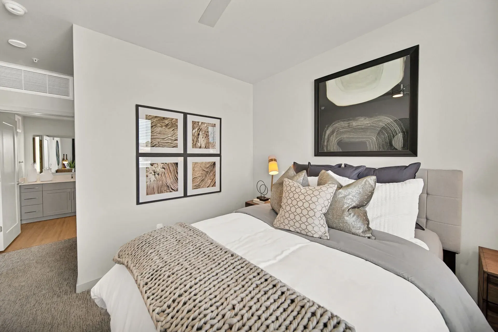 King-sized bed with decorative pillows and a cozy knit blanket in a modern bedroom.