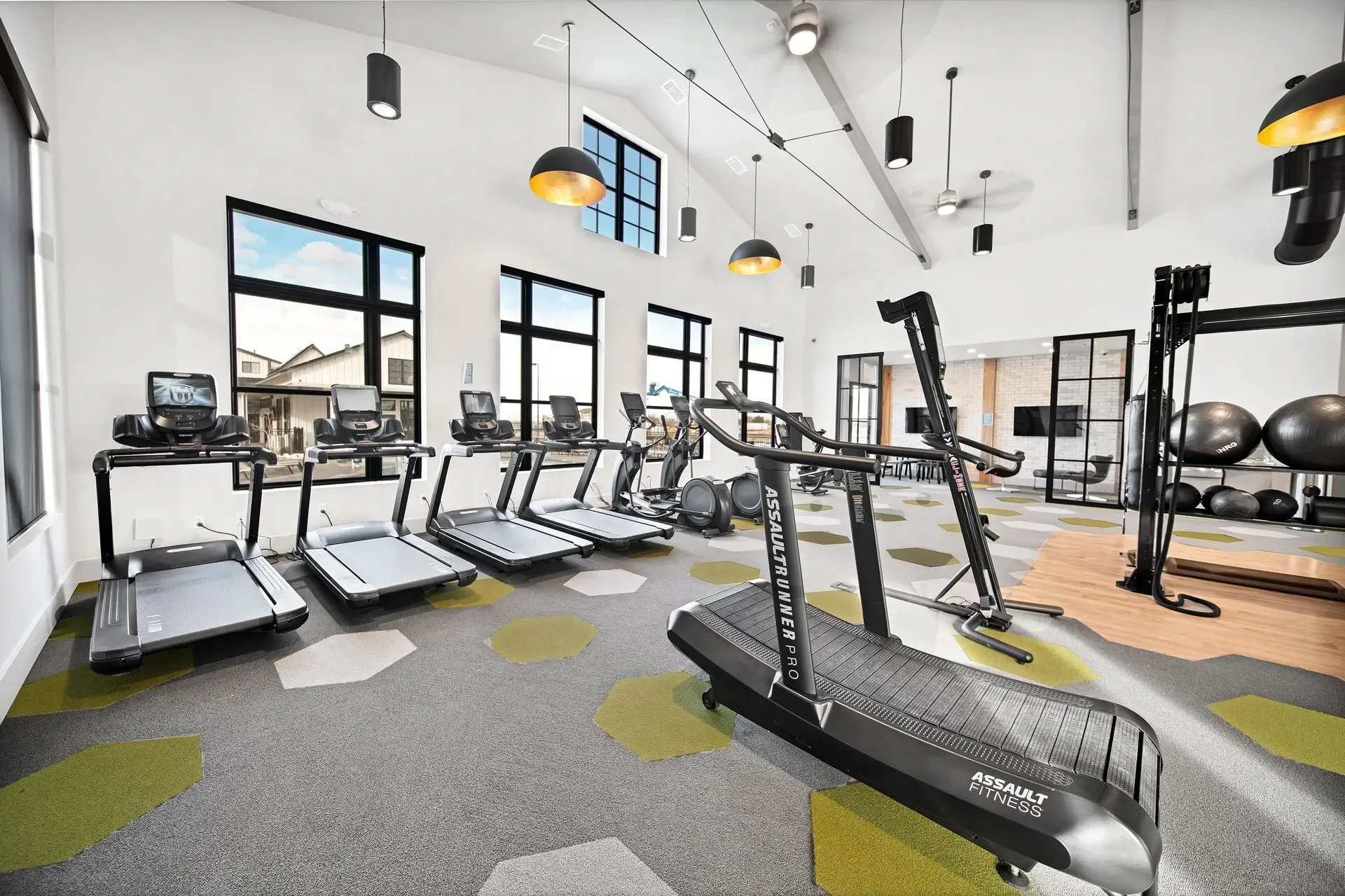 Modern fitness center with treadmills, ellipticals, and weight balls.