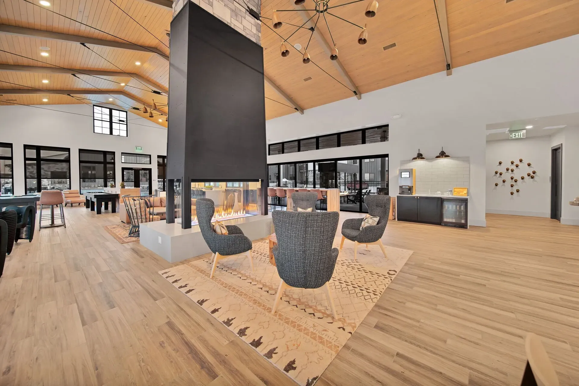 Modern community lounge with fireplace, seating, coffee bar, and pool table.