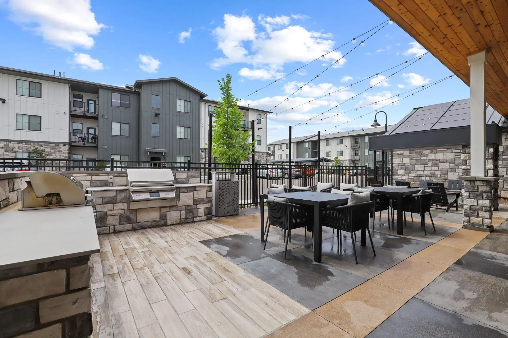 Outdoor grilling station with seating area and string lights.