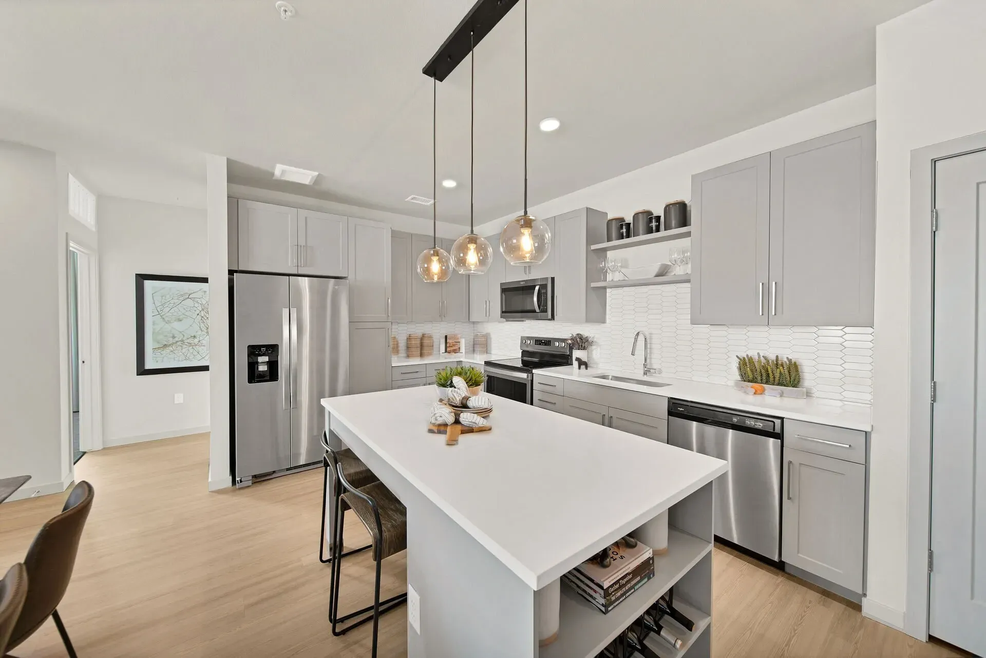 Modern kitchen with stainless steel appliances, gray cabinets, and an island with pendant lights.
