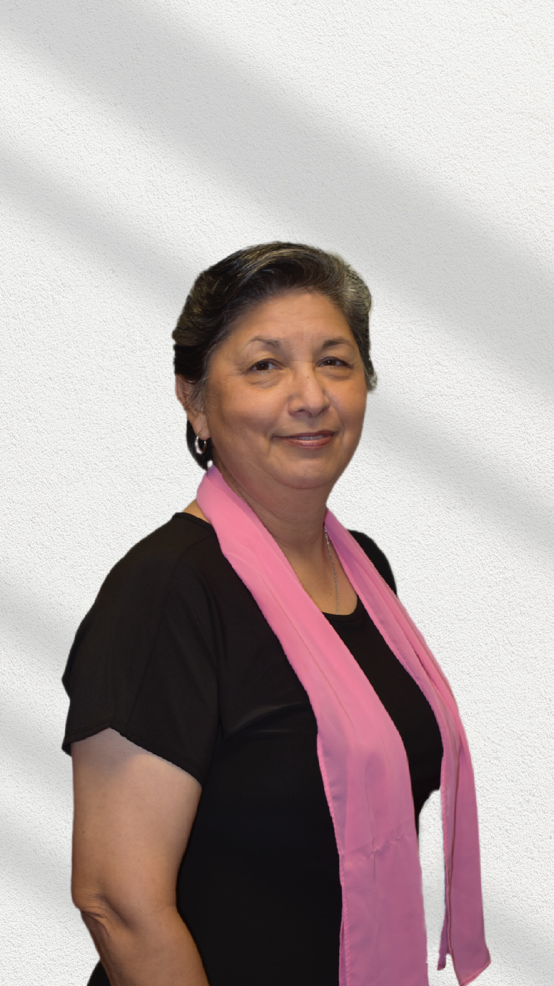 A woman wearing a black shirt and a pink scarf is smiling.