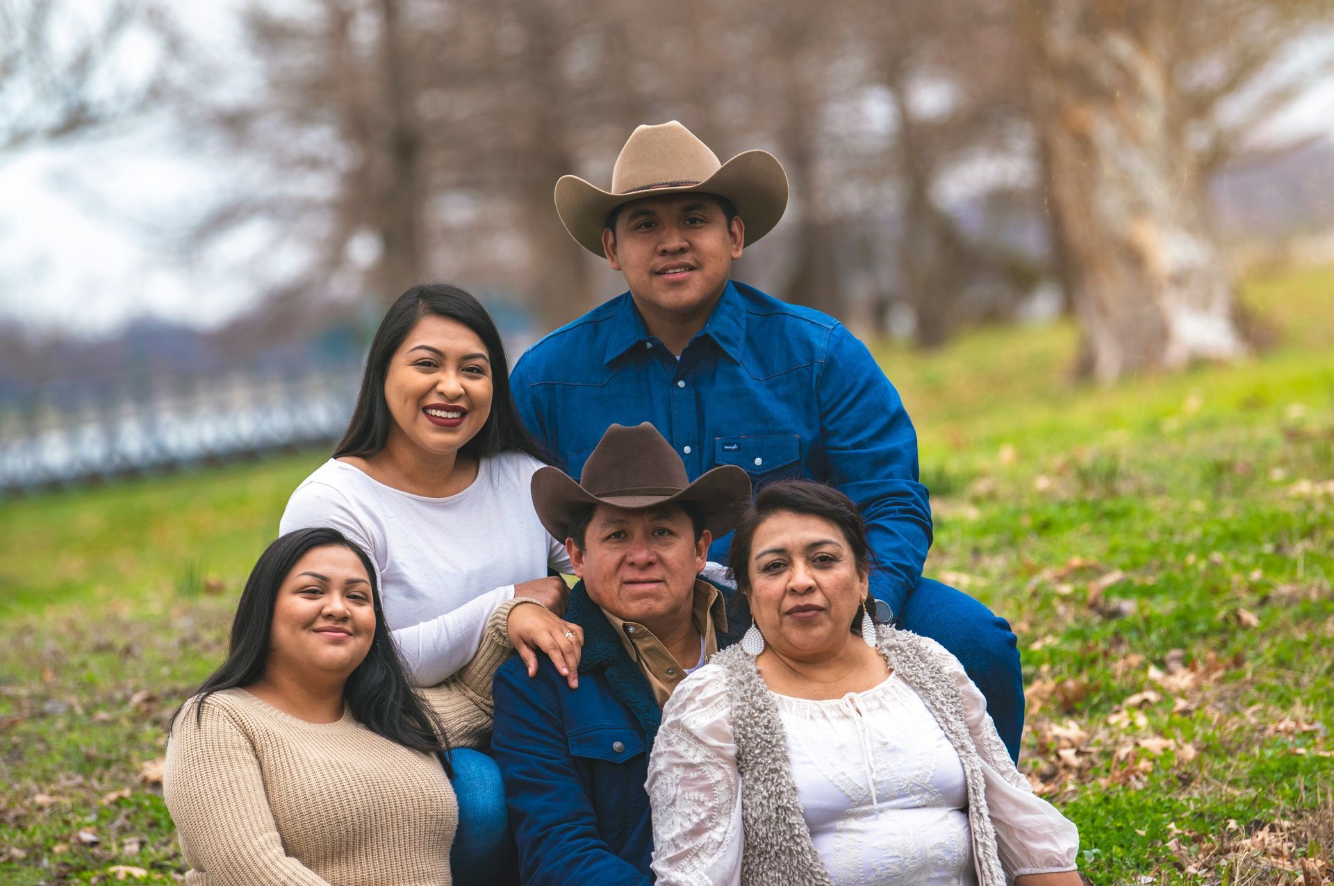 A woman in a red jacket with a fur hood is standing on a bridge in front of a city skyline.