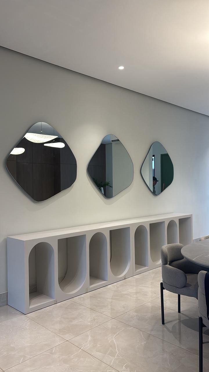 Una habitación con tres espejos en la pared y una mesa y sillas.