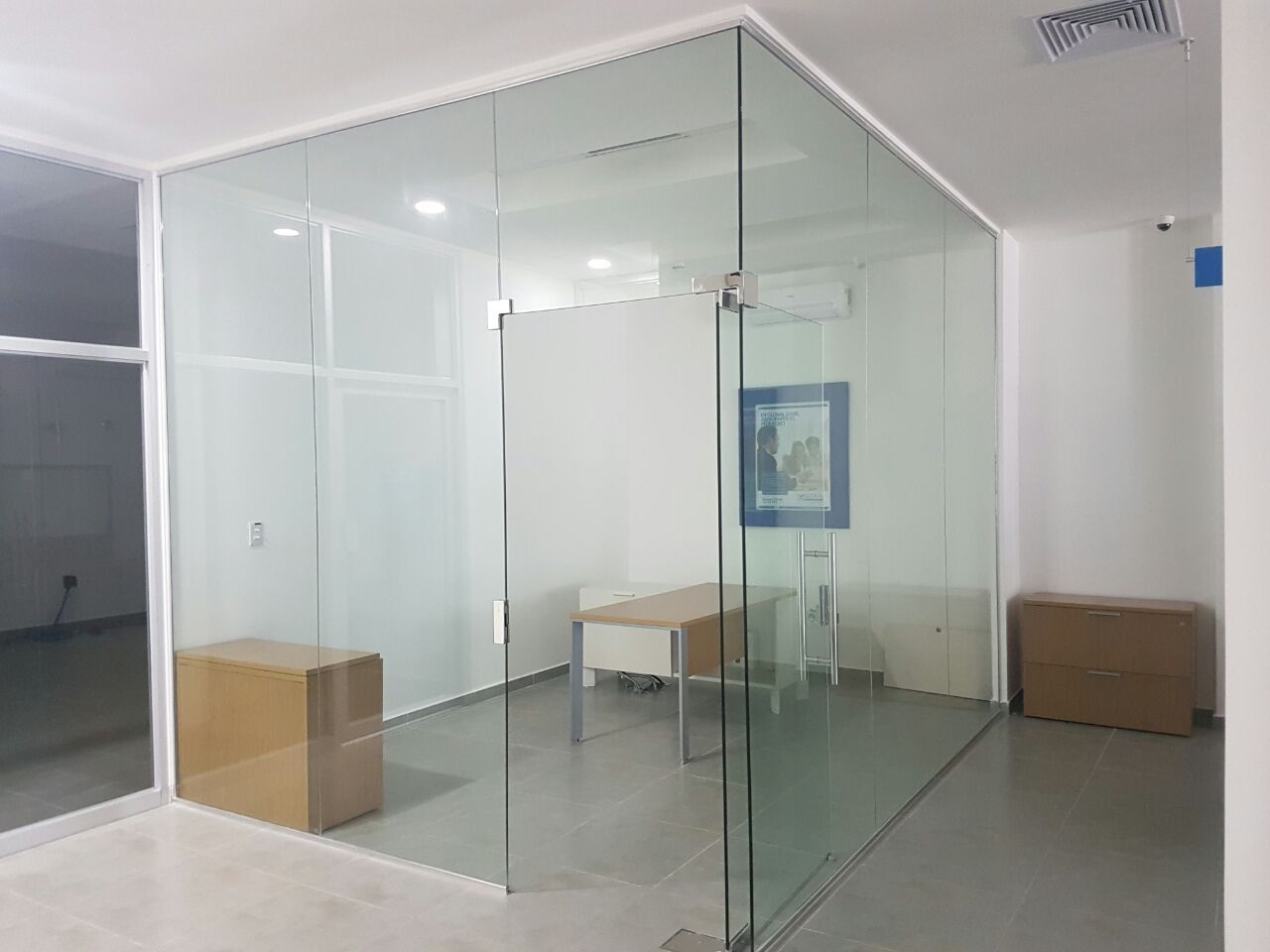 Una habitación con una pared de cristal y un escritorio dentro.