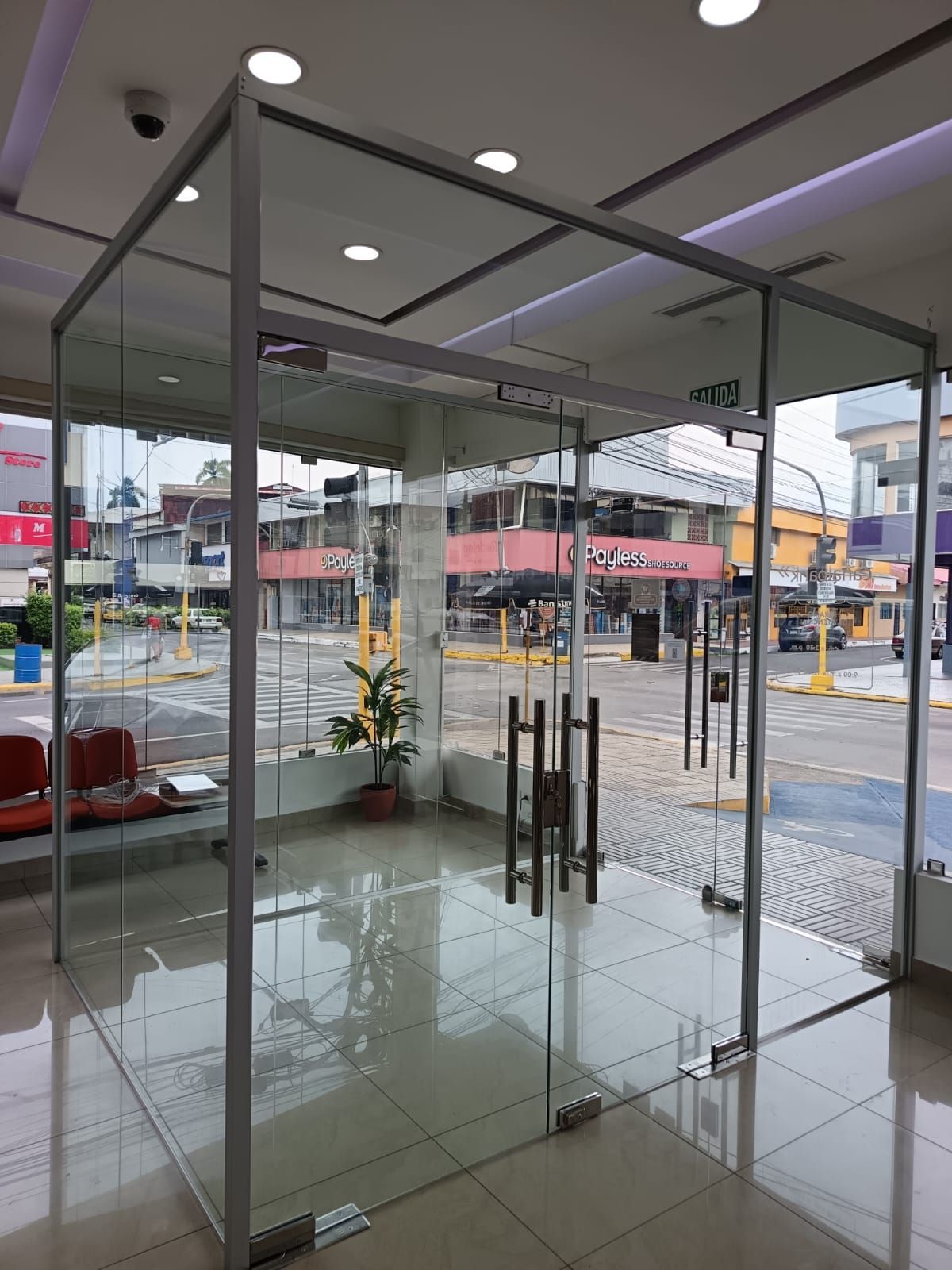 Una puerta de vidrio en un edificio con una silla roja al fondo.