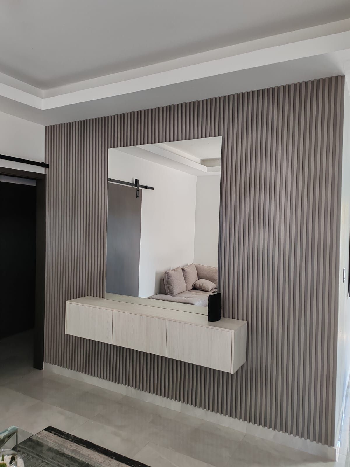 Una sala de estar con un sofá y un espejo en la pared.