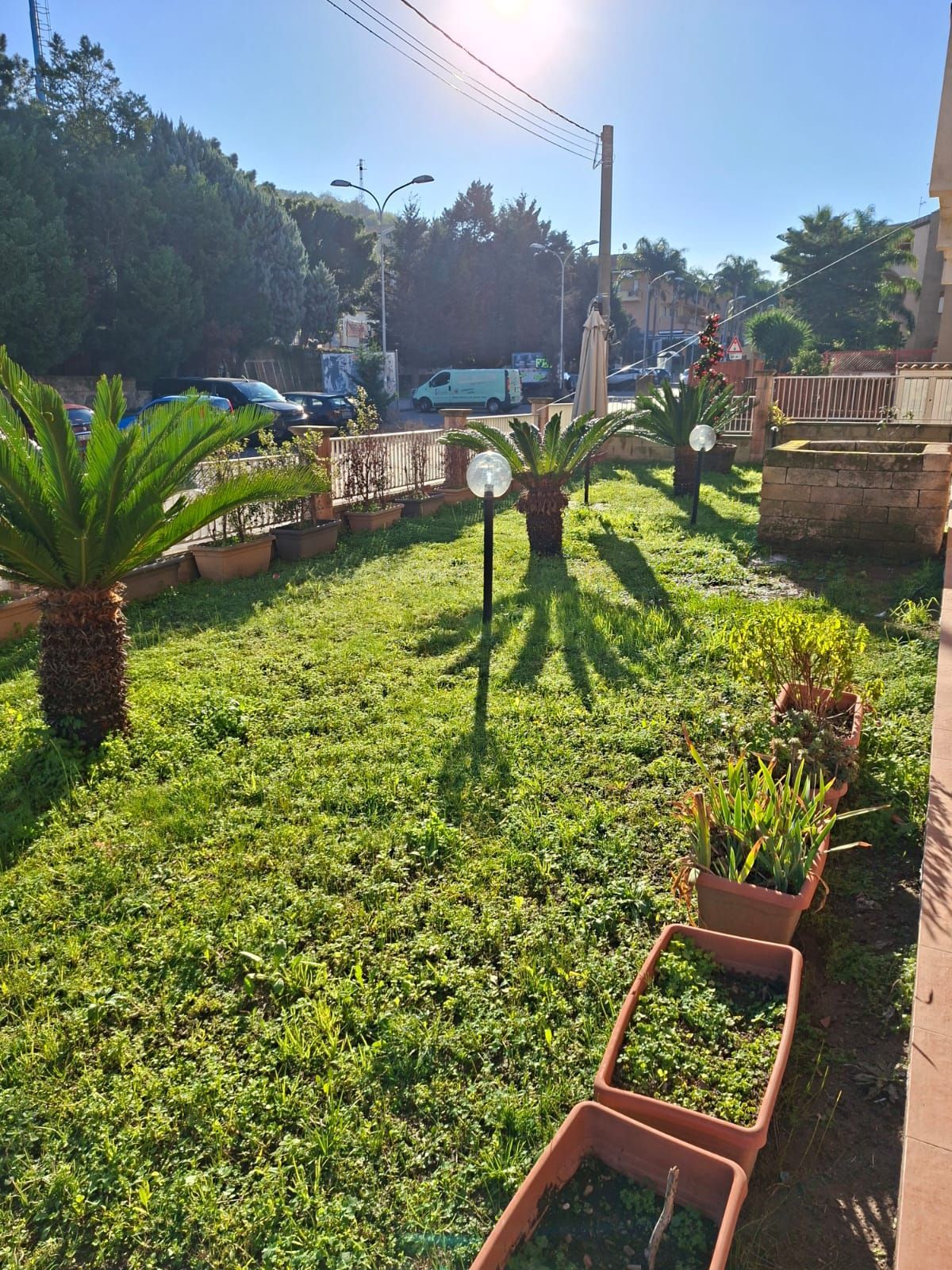 Una mano che mescola un cappuccino schiumoso in una tazza nera Mado, un croissant e dei bicchieri d'acqua su un tavolo.