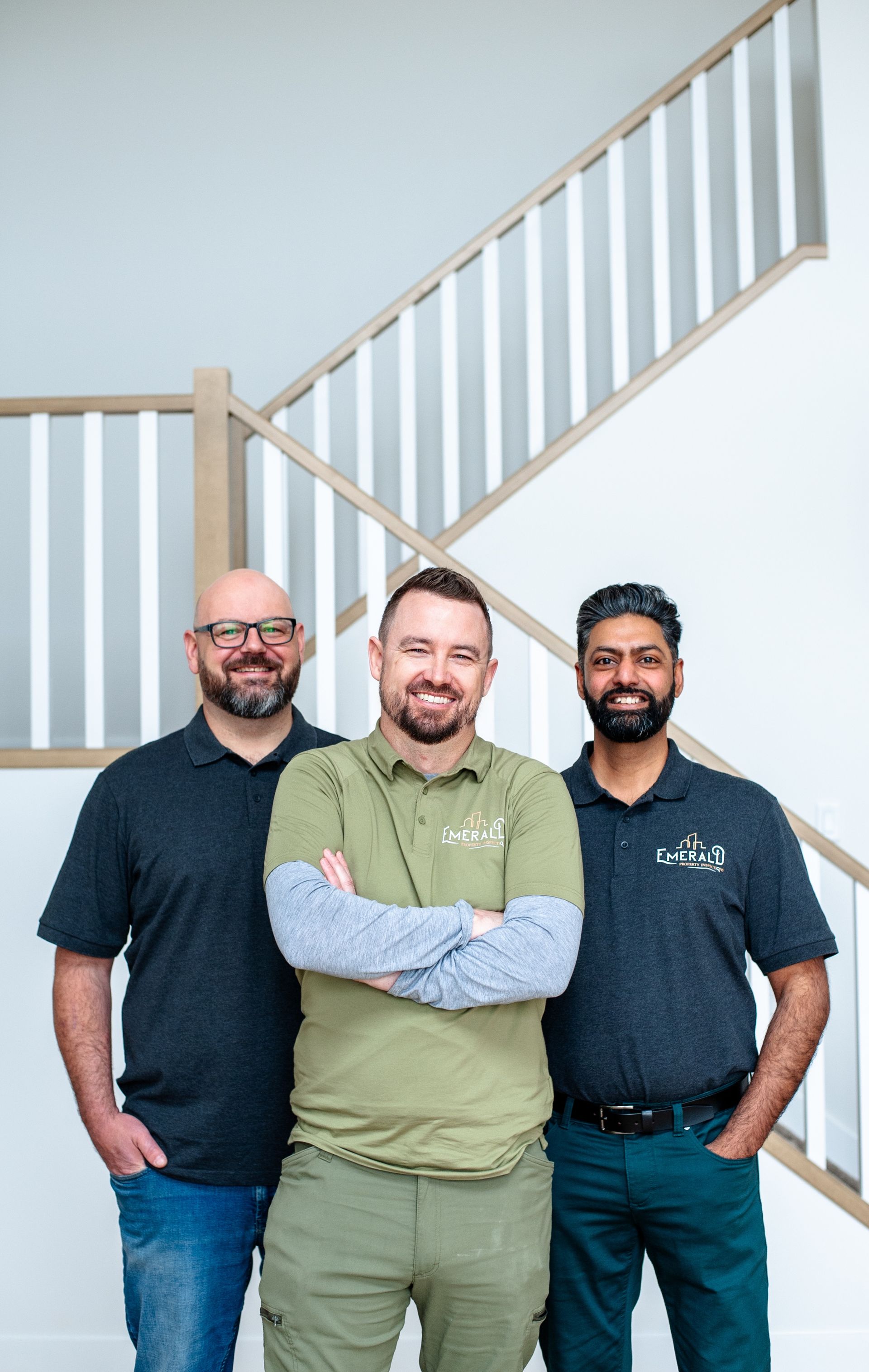 Three men are posing for a picture in front of a staircase.
