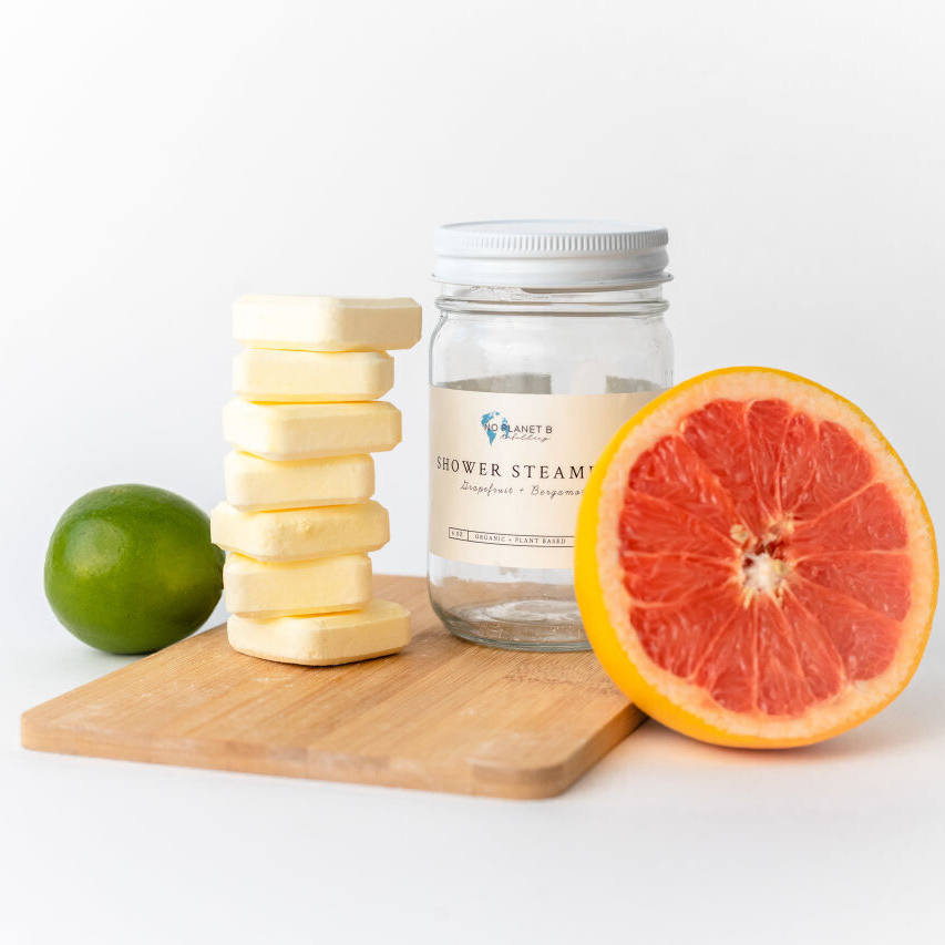 A jar of bath steam next to a grapefruit and a lime